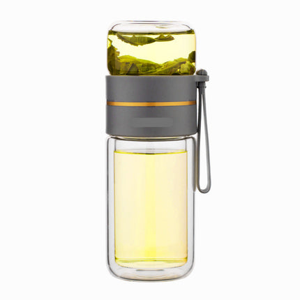 Clear glass bottle with a gray lid and handle, filled with yellow liquid and green leaves, on a white background.