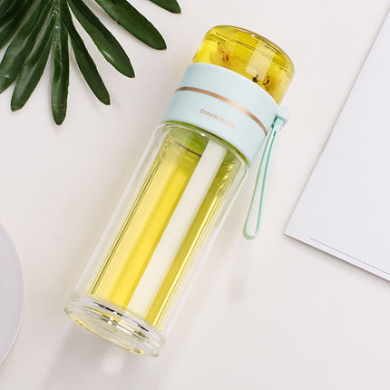 Clear water bottle with a yellow interior and light blue lid on a white surface with green leaves.