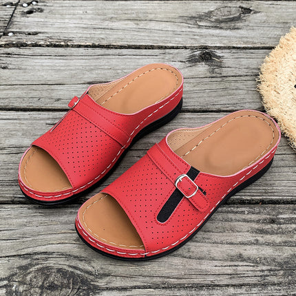 Red sandals with brown soles on a wooden surface