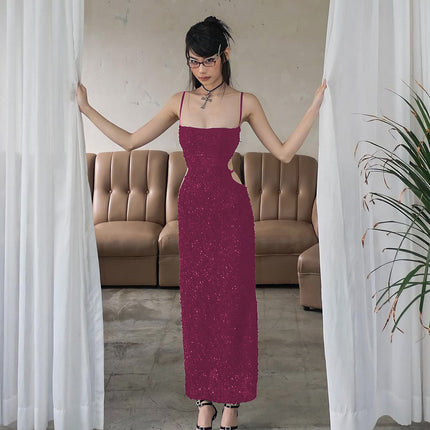 Woman in a long purple dress standing between white curtains in a room with a beige sofa.