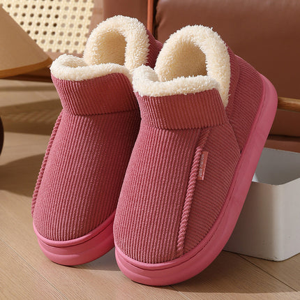 Pair of pink slippers with white fur lining on a wooden floor.
