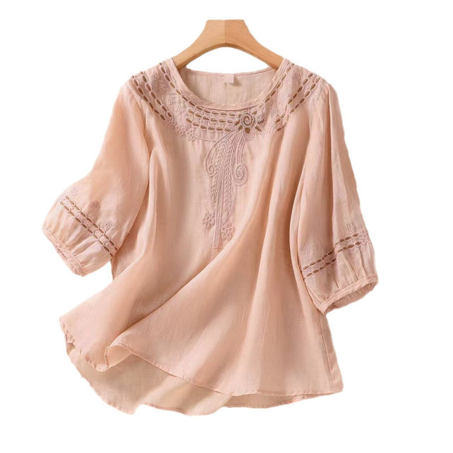 Pink blouse with lace details on a wooden hanger against a white background