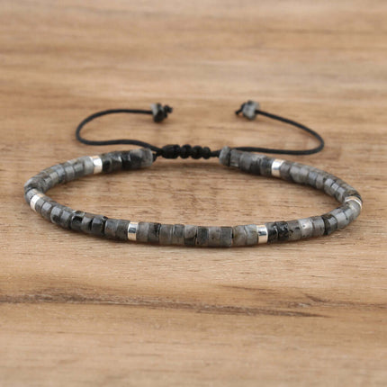 Adjustable beaded bracelet featuring dark gray natural stones and silver accents on a wooden surface.