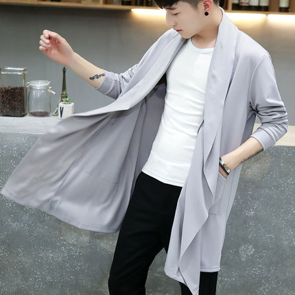 Person wearing a light gray cardigan over a white shirt and black pants, standing in a casual setting.