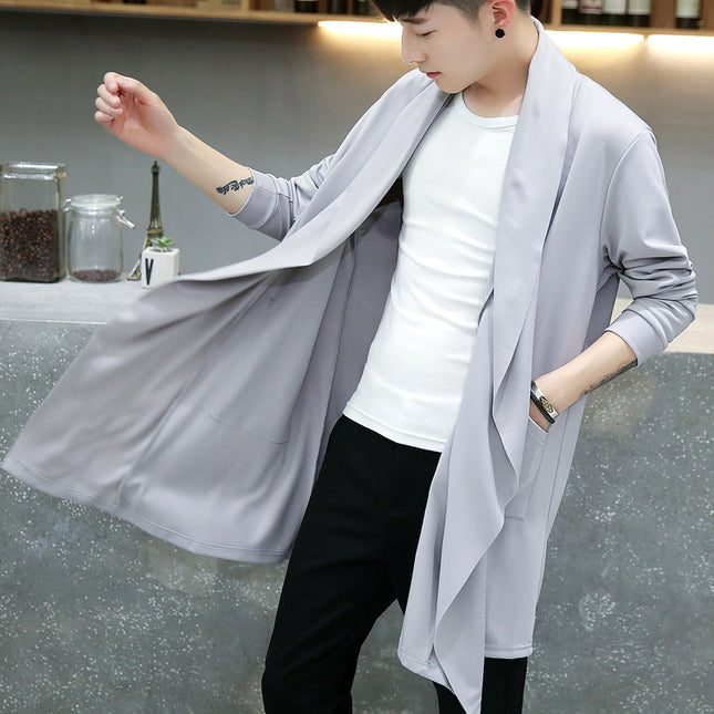 Person wearing a light gray cardigan over a white shirt and black pants, standing in a casual setting.