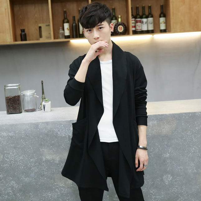 Man wearing a black cardigan over a white shirt in a casual setting.