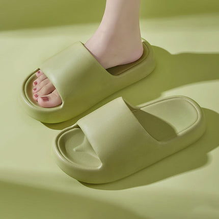 Green slippers worn by a person on a matching green background
