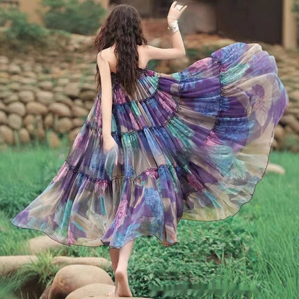 Woman in a colorful dress standing outdoors with greenery in the background