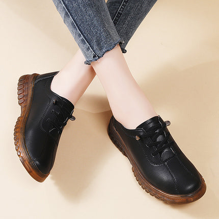 Black leather shoes with brown soles worn with blue jeans on a beige background