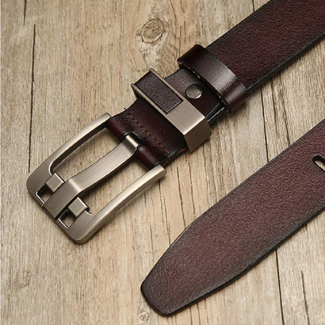 Brown leather belt with silver buckle on a wooden surface