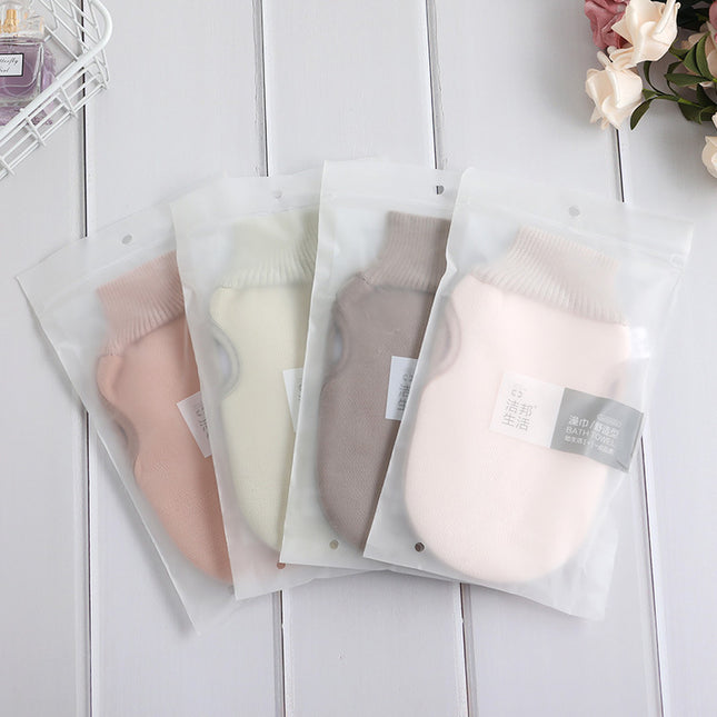 Four pairs of baby socks in clear packaging on a light wooden surface with flowers in the corner.