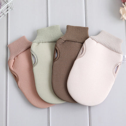 Four pairs of knitted dog sweaters in different colors on a white wooden surface.