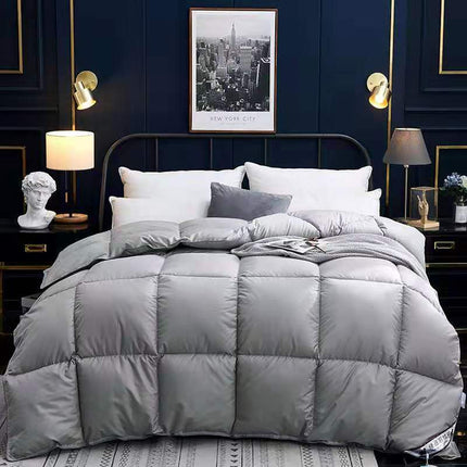 Gray quilted comforter on a bed in a stylish bedroom with dark walls and decorative elements.