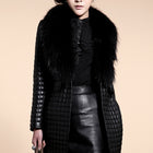 Woman wearing a black coat with fur collar and leather skirt on a beige background