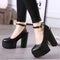 Black platform shoes worn with black pants on a neutral background