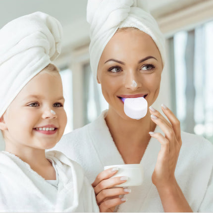 Woman and child with towels on heads, woman blowing bubble, blurred background