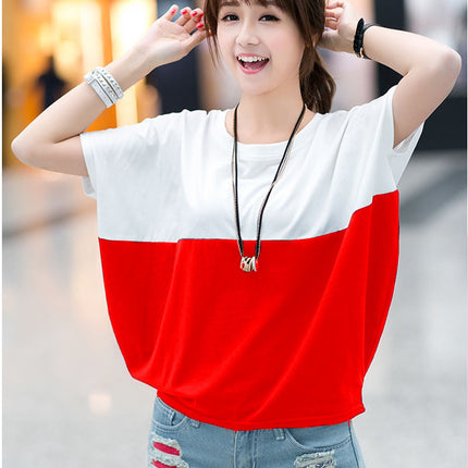 Woman wearing a red and white color-blocked top with denim shorts in an outdoor setting.