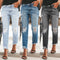 Three pairs of distressed jeans worn by different people on a blurred background.