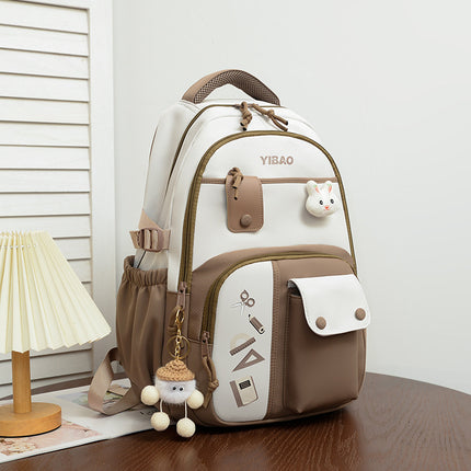 Brown and white backpack with decorative elements on a wooden surface.