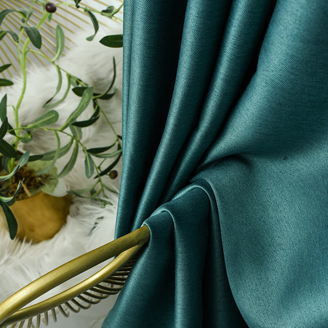 Teal fabric with gold decorative elements and a plant in the background