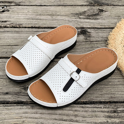 White sandals with brown soles on a wooden surface