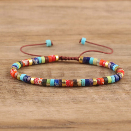 Colorful handmade spacer bead bracelet with an adjustable closure on a wooden background.