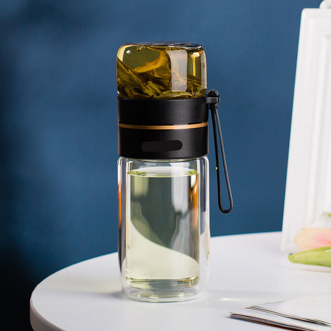 Clear glass bottle with black lid and handle on a white surface with a blue background
