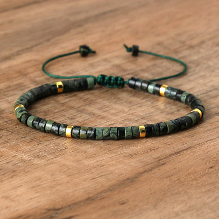Hand-woven adjustable bracelet featuring green and black spacer beads with golden accents on a wooden background.