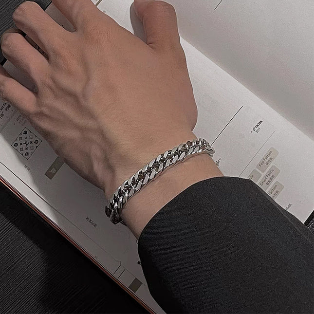 Hand wearing a silver chain bracelet on a blurred background