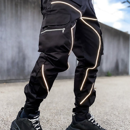 Person wearing black reflective pants with white stripes on a concrete surface.