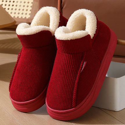 Red slippers with white fur lining on a wooden floor.