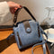 Blue handbag with a strap held by a hand on a wooden surface.
