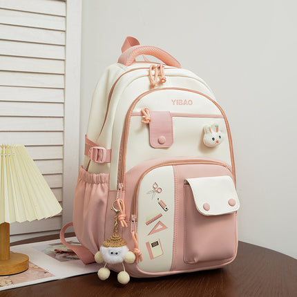 Pink and white backpack with decorative elements on a wooden surface.