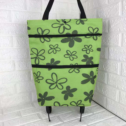 Green tote bag with black floral pattern on a white tiled floor.