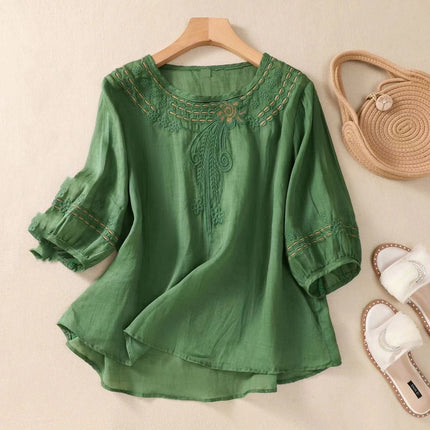 Green embroidered blouse on a hanger with a beige background