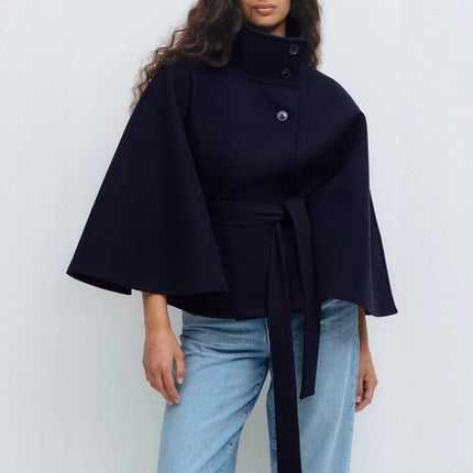 Person wearing a black cape over a plain background