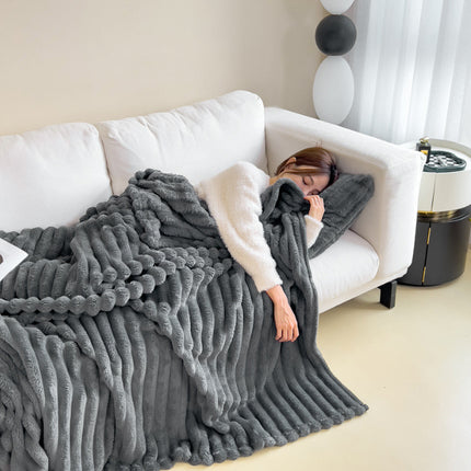 Person lying on a white couch under a gray blanket in a modern living room.