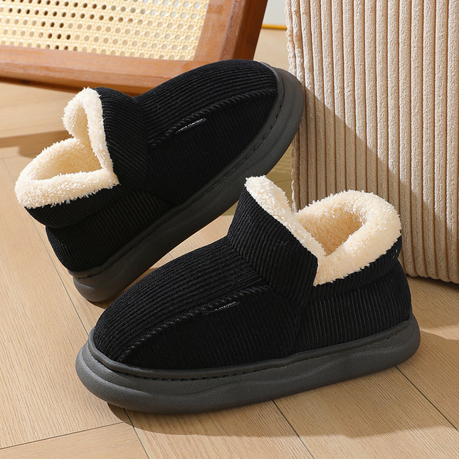 Black slip-on shoes with cream interior on a wooden floor