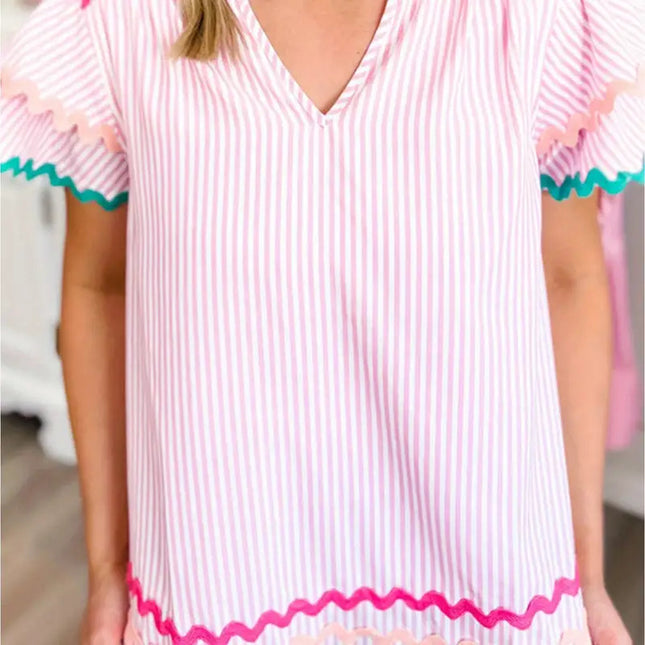 Woman wearing a pink and white striped dress with colorful trim.