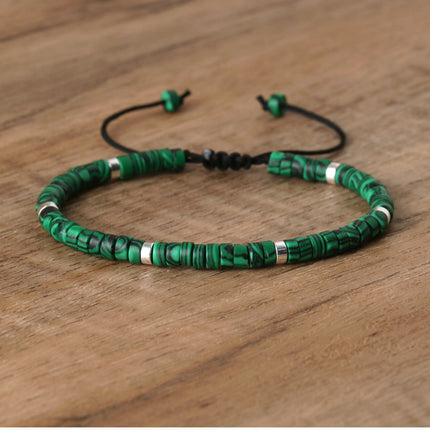 Adjustable green stone spacer beads bracelet for women, hand-woven with silver accents on a wooden surface.