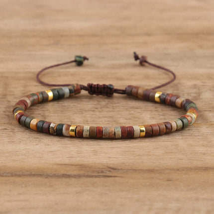 Hand-woven adjustable spacer beads bracelet featuring natural stones and gold accents on a wooden background.