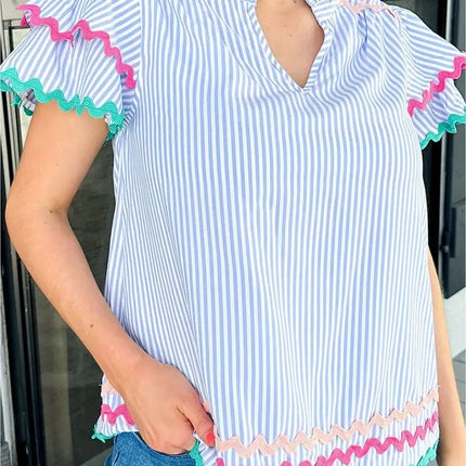 Woman wearing a blue and white striped dress with colorful ruffled edges.