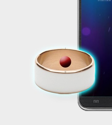Small round device with a red ball inside next to a smartphone on a white background