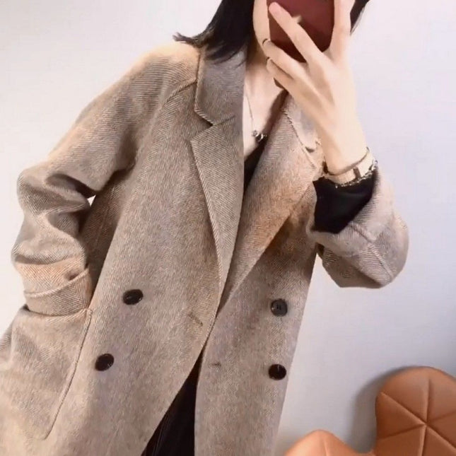 Person wearing a beige coat with black buttons against a plain background