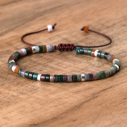Hand-woven adjustable spacer bead bracelet featuring colorful natural stones on a wooden background.