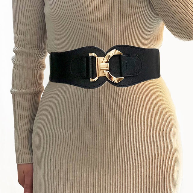 Black belt with a gold buckle worn by a person in a beige ribbed sweater and skirt.