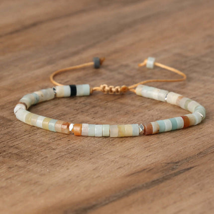 Adjustable beaded bracelet with natural stones, featuring shades of green, orange, and brown on a wooden background.