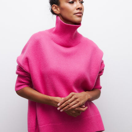 Person wearing a bright pink turtleneck sweater against a plain background