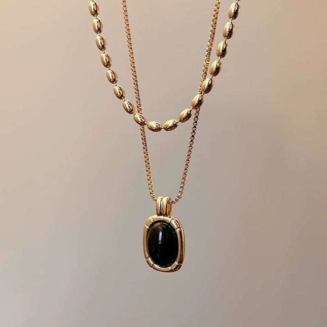 Gold necklace with a black pendant on a blurred background