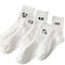 Four white socks with black smiley face designs on a white background